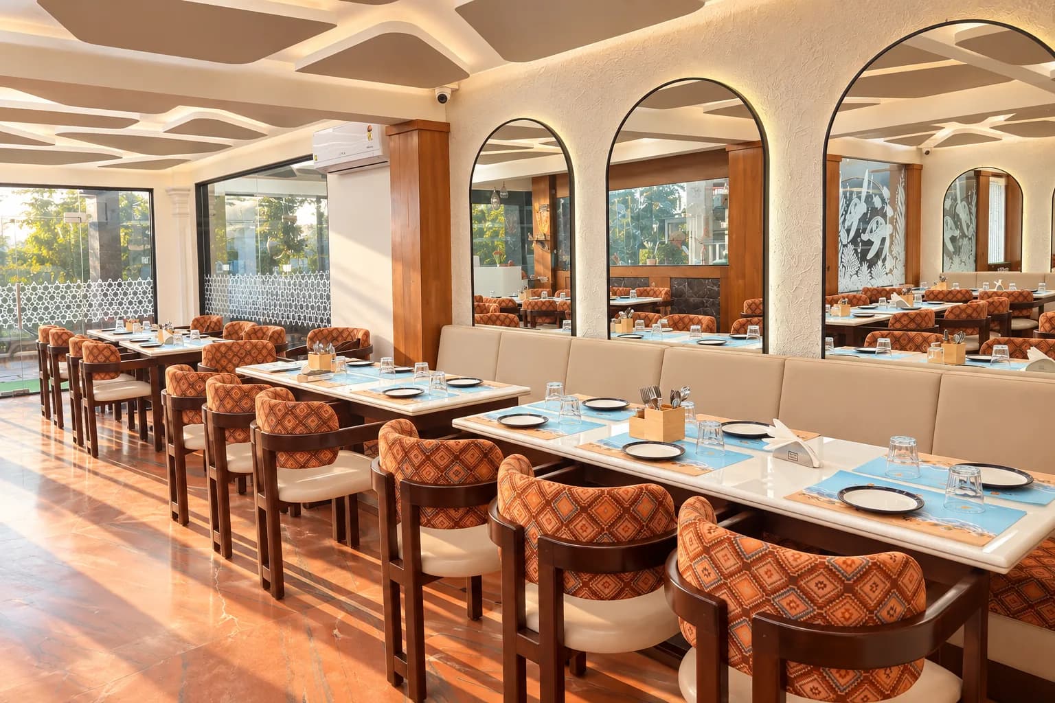 Inside Sea Swad — arched mirrors, rust-and-cream woven chairs and tables laid in sea blue.