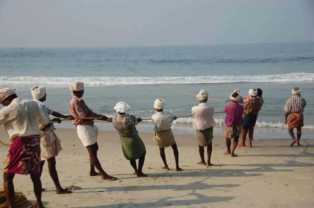 A line of fishermen hauling a shore net out of the surf