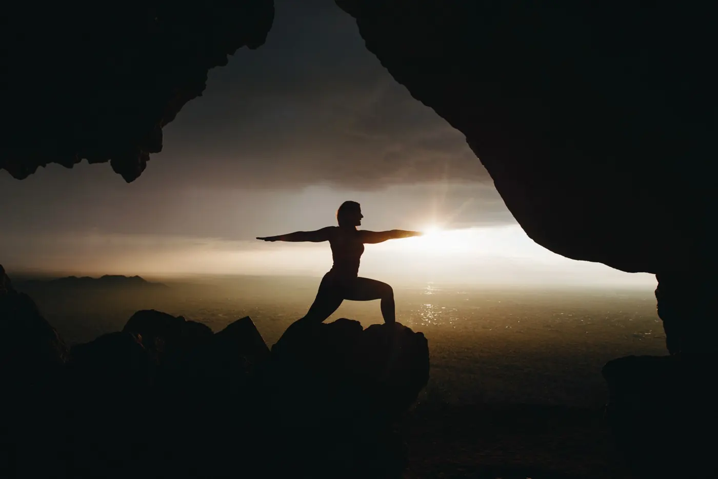 A silhouette holding a yoga pose against the sunrise
